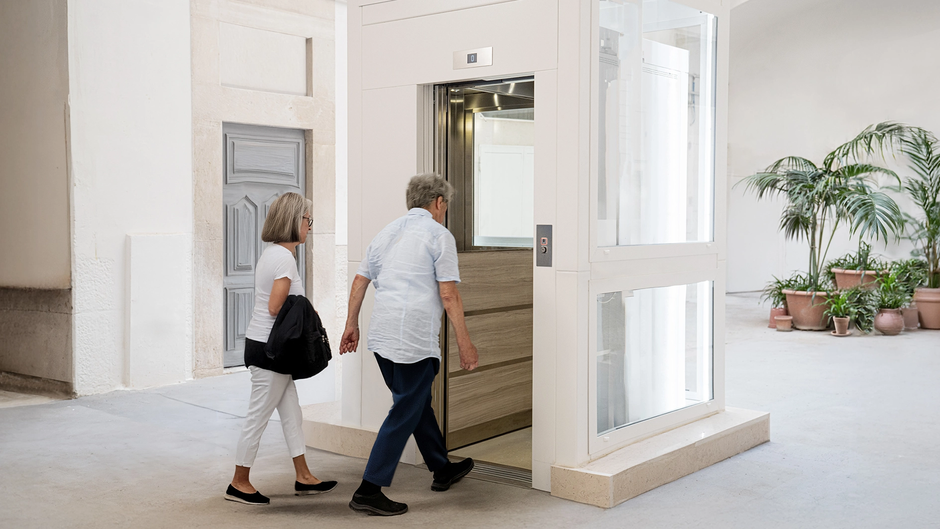 due persone anziane entrano in un ascensore compatto per edifici esistenti